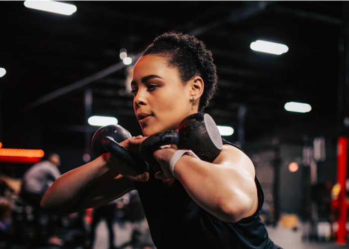 A woman working working out with a pair of kettlebells